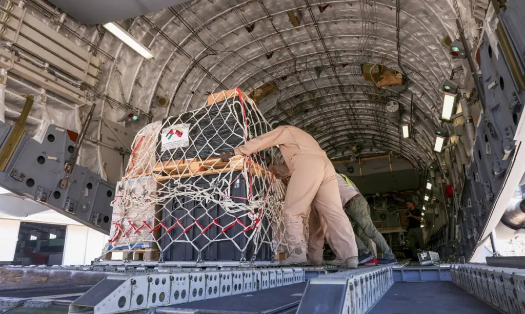 Militares carregam carga de ajuda humanitária em aeronave de transporte