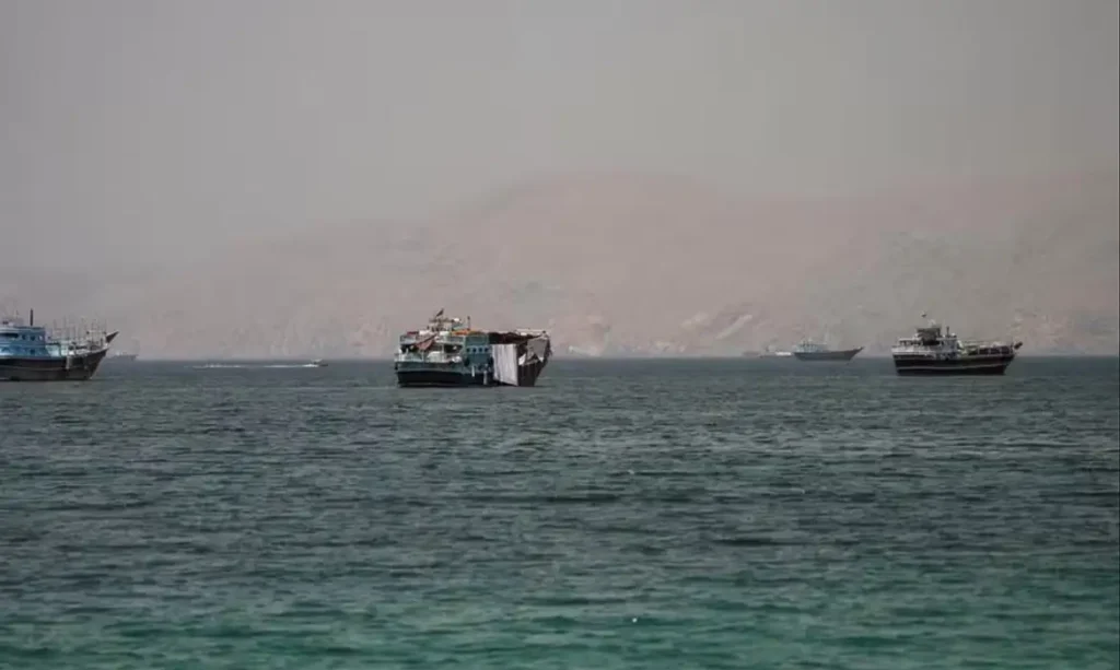 Barcos navegam em estreito com montanhas ao fundo