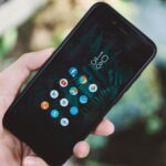 Mão segurando celular com aplicativos