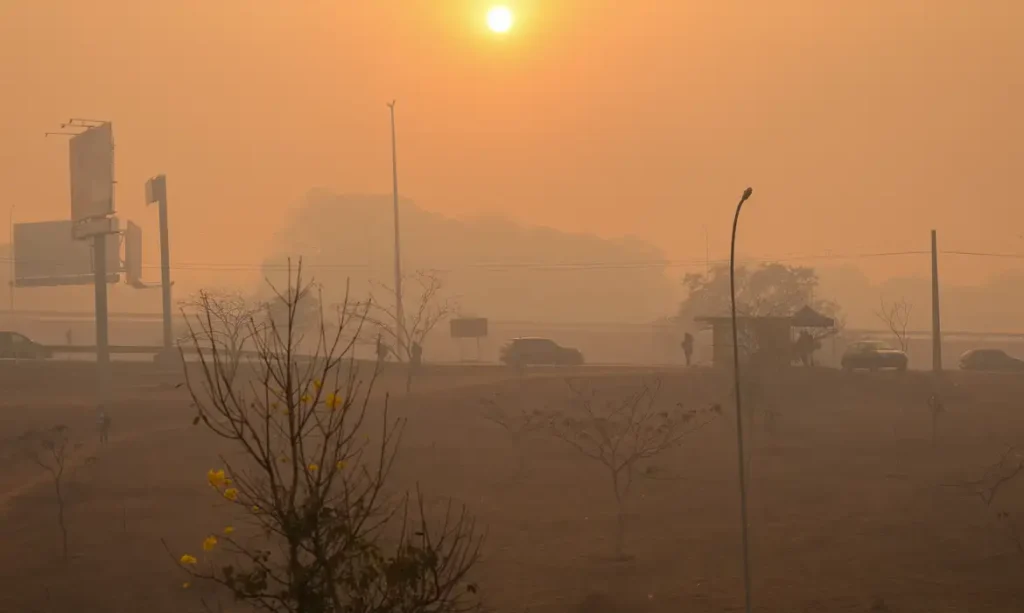 Sol aparece encoberto por neblina seca durante entardecer