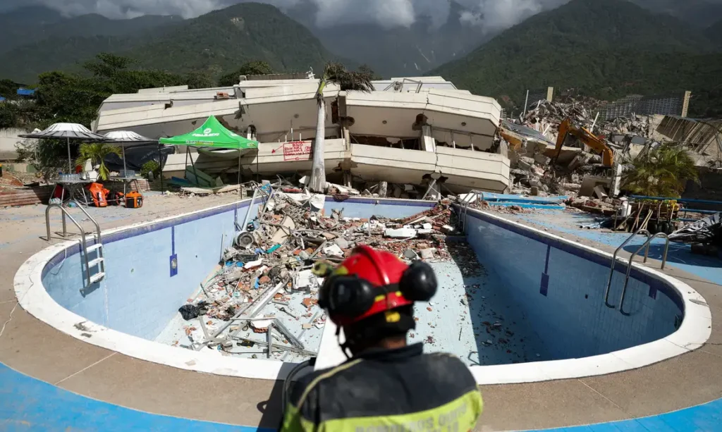 Resgatista observa escombros de prédio desabado sobre piscina após terremoto